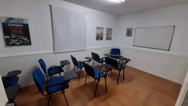 Aula de Academia Ecu con pupitres, pizarra blanca y paredes claras